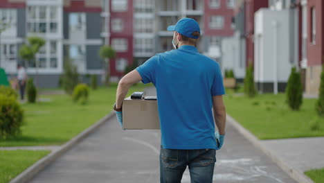 A-delivery-man-carries-a-package-to-customers-in-a-residential-area.-Grocery-delivery-and-online-shopping