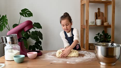 Cute-Little-Girl-Kneading-Dough-On-Table