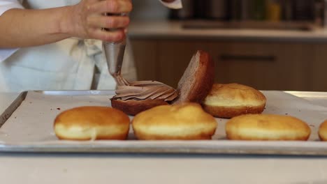 Panadero-Irreconocible-Añadiendo-Crema-A-Los-Pasteles-En-La-Cocina