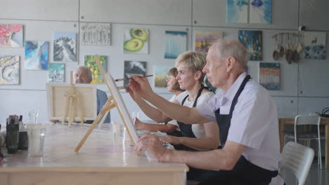 The-teacher-shows-a-group-of-friends-of-retired-people-in-the-elderly-at-drawing-courses.-A-group-of-elderly-men-and-women-draw-together-and-smile