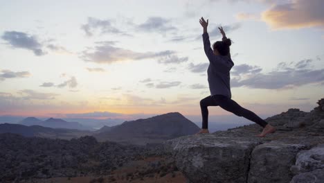 Concentrated-woman-practicing-yoga-in-mountains-at-sunset