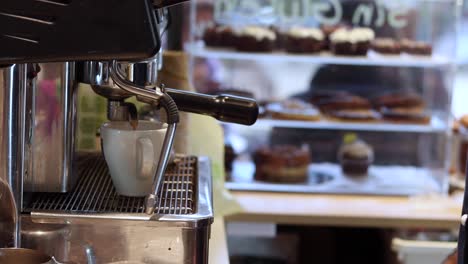 Crop-barista-preparing-drink-in-coffee-machine