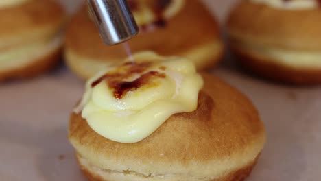 Crop-cook-burning-cream-on-dessert-with-gas-burner-in-bakery