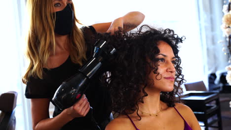 Professional-hairdresser-making-hairdo-to-long-haired-female-customer