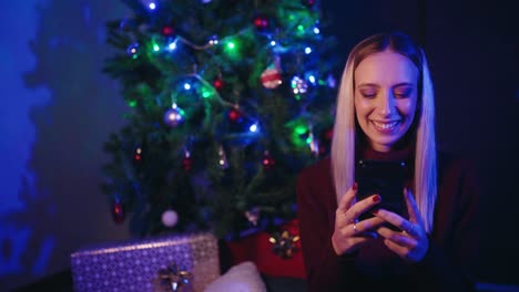 Frau-Benutzt-Smartphone-In-Der-Nähe-Des-Weihnachtsbaums