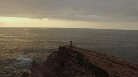 Loving-couple-kissing-on-rocky-cliff-near-sea