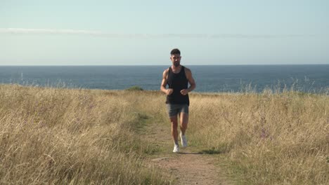 Man-running-along-path-at-seaside