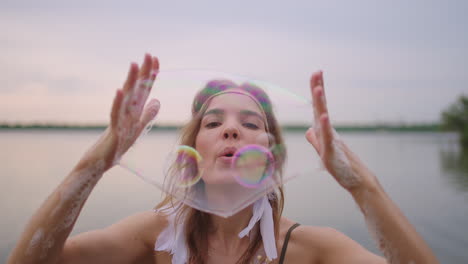 A-young-girl-artist-shows-magic-tricks-using-soap-bubbles.-Create-soap-bubbles-in-your-hands-and-inflate-them-location-theatrical-circus-show-at-sunset