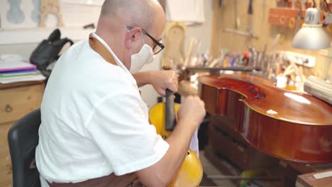 Craftsman-with-violin-in-professional-workshop