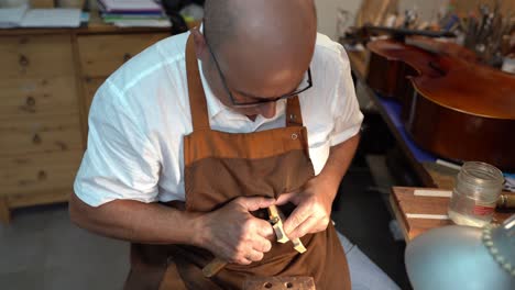 Luthier-with-violin-bridge-in-workshop