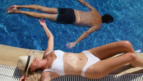 Young-woman-sunbathing-on-poolside-in-resort