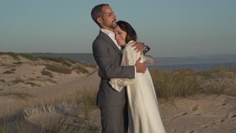 Newlywed-couple-embracing-at-seaside