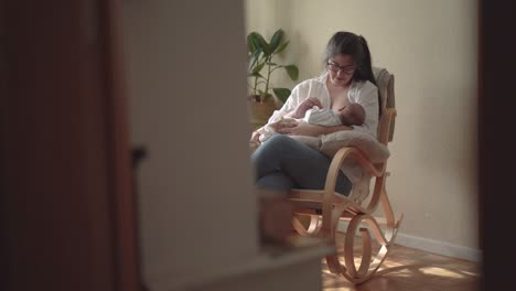 Mother-breastfeeding-unrecognizable-newborn-baby-in-rocking-chair
