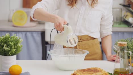 Anonymous-woman-chef-using-a-mixer-whipping-a-batter