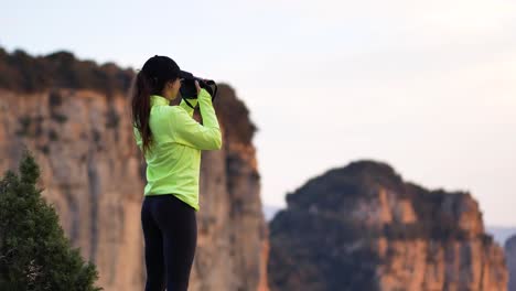 Young-woman-photographing-mountains-on-camera