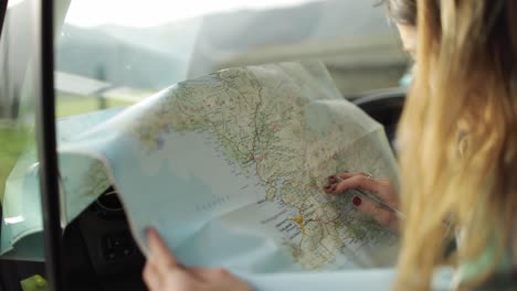 Driver-writing-on-paper-map-in-car-during-trip