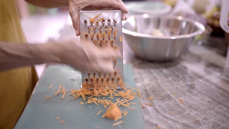 Crop-woman-grating-fresh-carrot-in-kitchen