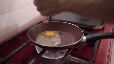 Old-person-breaking-eggs-on-frying-pan