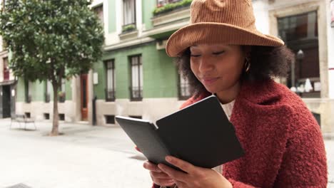 Mujer-Negra-Leyendo-Un-Libro-Electrónico-En-La-Ciudad