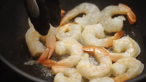 Unrecognizable-cook-frying-prawns-in-pan-with-hot-oil