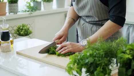Woman-cutting-parsley-on-wooden-board
