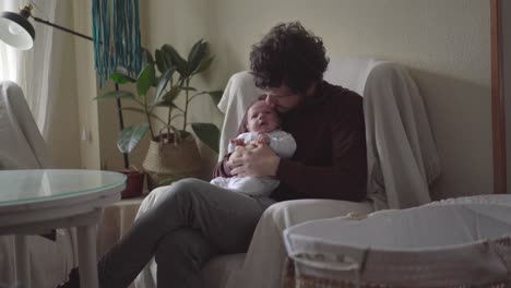 Dad-embracing-newborn-baby-in-armchair-at-home