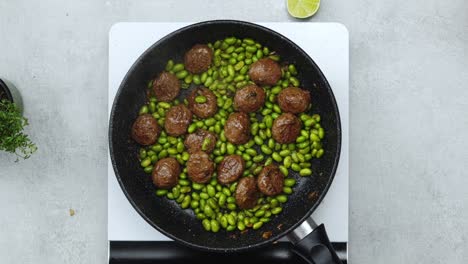 Woman-adding-peanuts-to-meatballs-with-beans