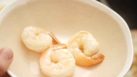 Unrecognizable-person-putting-fried-prawns-from-pan-into-bowl