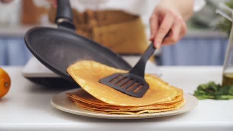 Anonymous-cook-putting-a-pancake-on-top-of-another-pancake