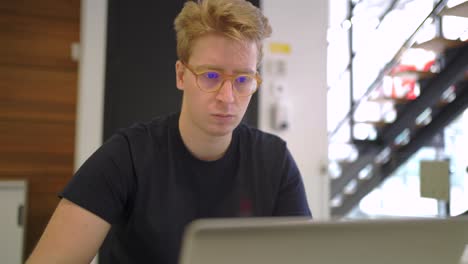 Man-in-eyeglasses-working-on-laptop-in-office
