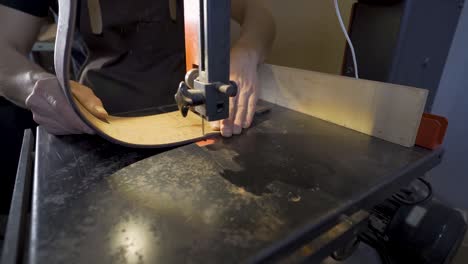 Anonymous-luthier-cutting-guitar-body-on-bandsaw-in-workroom