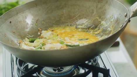 Woman-adding-rice-noodles-to-ingredients-in-frying-pan