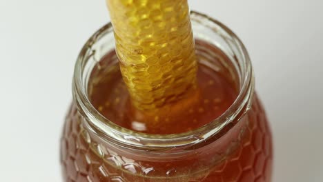 Person-taking-honeycomb-from-jar-with-honey