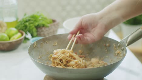 Woman-stirring-hot-wok-noodles-with-chopsticks