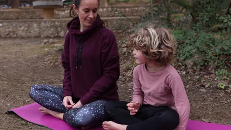 Madre-Con-Hijo-Meditando-Sobre-Una-Estera-De-Yoga-En-El-Parque