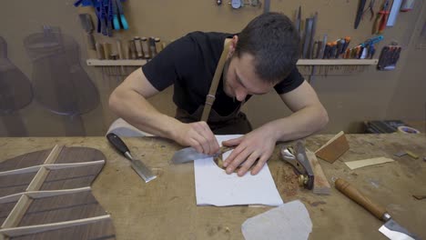 Craftsman-flattening-wooden-piece-with-scraper-in-workroom