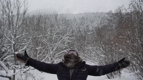Content-woman-in-outerwear-outstretching-arms-in-winter-forest