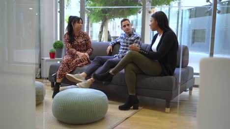 Multiethnic-colleagues-sitting-on-couch-in-office