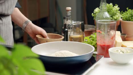 Cook-pouring-rice-into-pan-while-preparing-dish
