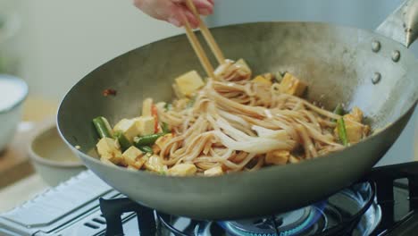 Woman-mixing-delicious-wok-noodles-with-chopsticks