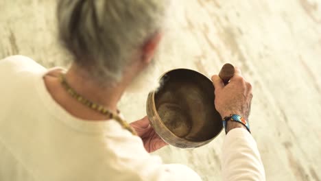 Senior-man-playing-bowl-gong-with-mallet
