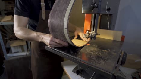 Anonymous-luthier-cutting-guitar-body-on-bandsaw-in-workroom