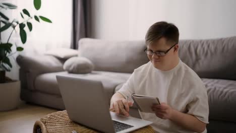 Down-syndrome-adult-man-sitting-at-home,-using-laptop-for-learning