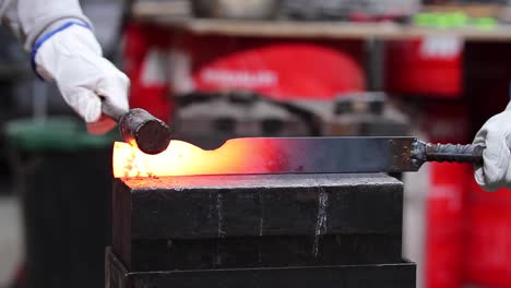 Blacksmiths-forging-hot-metal-with-hammer-in-workshop