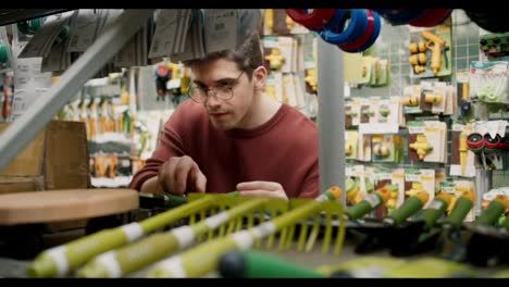 Exploring-Gardening-Equipment-at-a-Specialized-Store-with-a-Young-Man-in-Brown-Sweater-and-Glasses