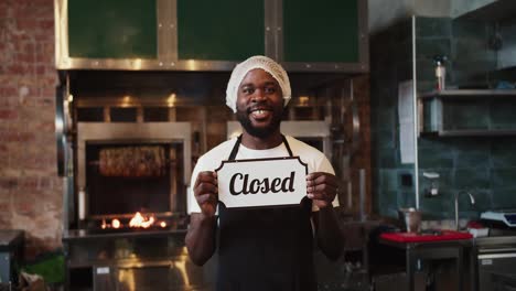 A-Black-person-in-a-special-headdress-poses-with-a-Close-sign-against-the-background-of-a-barbecue-in-a-doner-market.-Video-filmed-in-high-quality