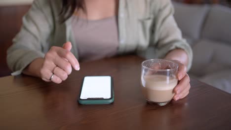 Crop-anonymous-woman-with-latte-touching-screen-on-smartphone