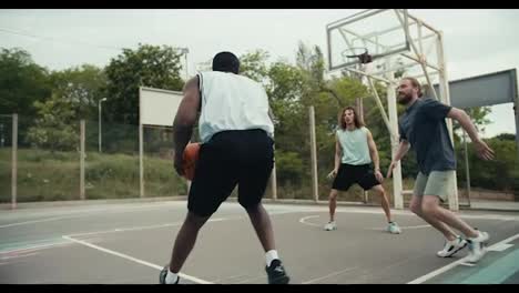 A-group-of-friends-are-playing-basketball.-A-black-person-dribbles,-a-man-tries-to-score-a-goal-and-his-friends-help-him