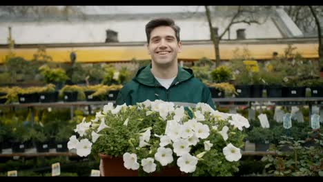 Botanical-Beauty:-Smiling-Florist-Holding-Plants-in-Green-Uniform-at-Specialized-Store
