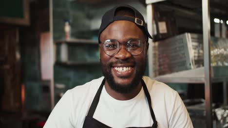 Portrait-of-a-Black-person-in-a-doner-market.-Man-with-glasses-posing-and-smiling